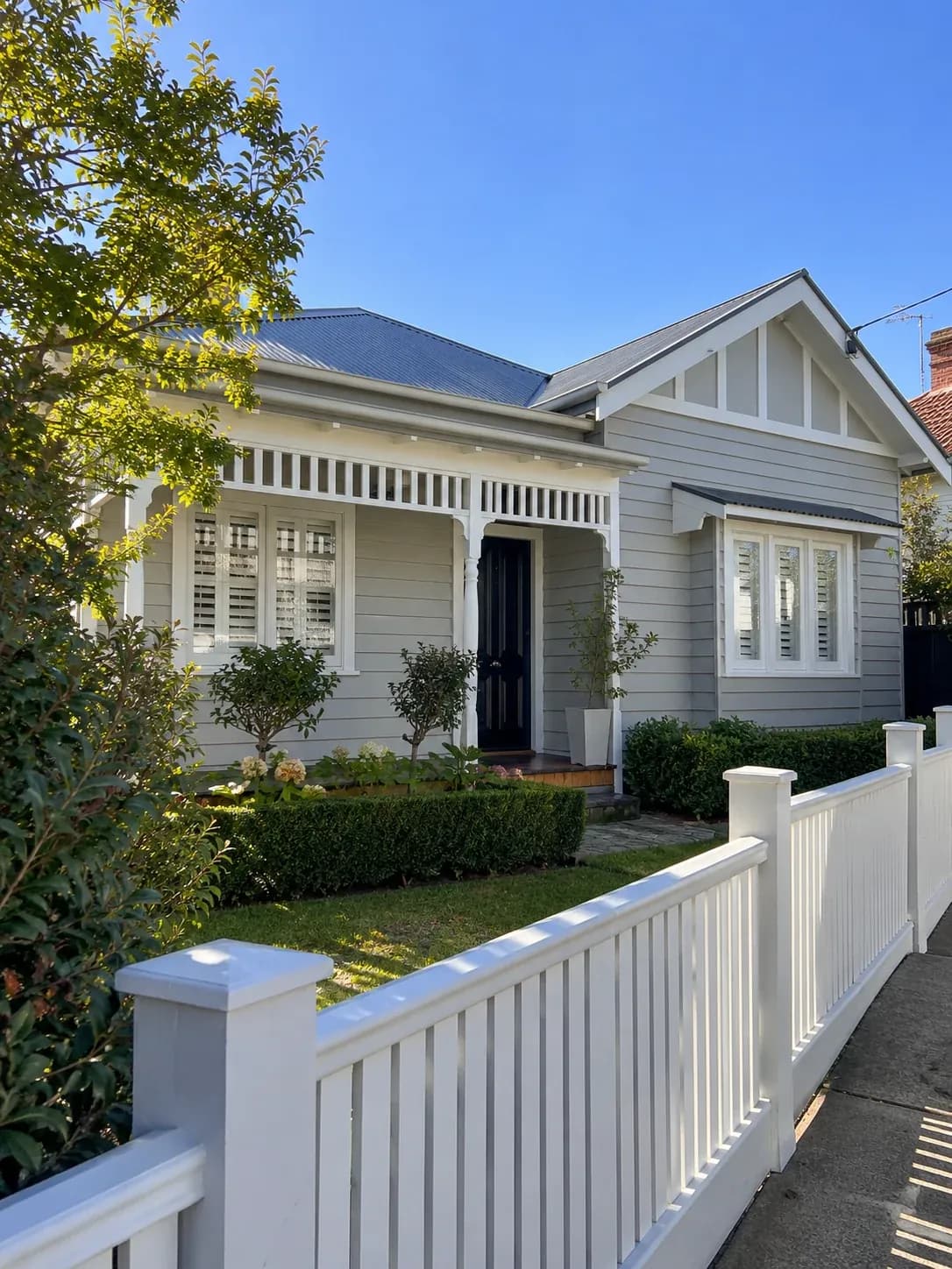 Weatherboard house exterior freshly painted in light grey with white trims